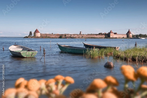 Fototapeta  old boats on Lake Ladoga against the background of the ancient  fortress Oreshek in summer sunny day