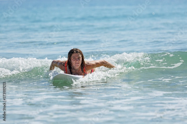 Obraz girl on a surfboard swims on the sea, summer, sunny day, clear water