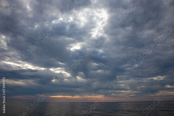 Fototapeta Seascape. Waves and surf. Sunset and dawn at sea. Calm on the ocean. Beautiful sky and clouds illuminated by the sun. Natural background. Summer time.
