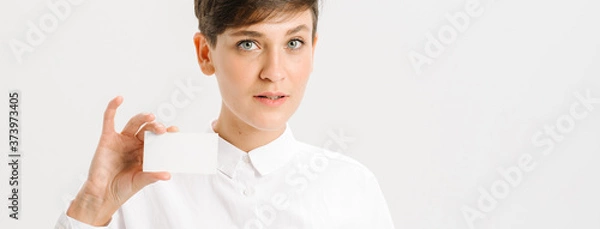 Fototapeta  girl in a white office shirt holds out a business card. close portrait.