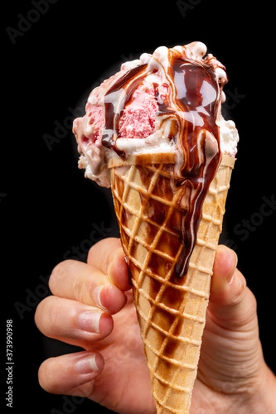 Fototapeta Tasty wafer ice cream in hand with chocolate glaze. Fruit dessert in a crispy wafer.