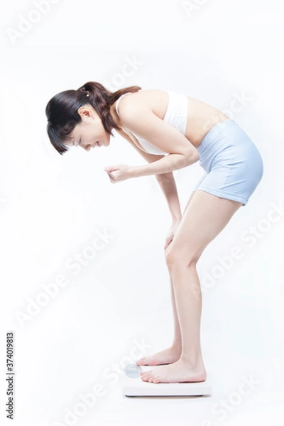 Obraz 体重計に乗ってガッツポーズする女性