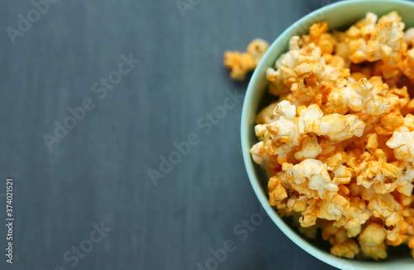 Fototapeta Delicious cheese popcorn in a blue dish on a gray background. Selective focus. Space for text. Copy space