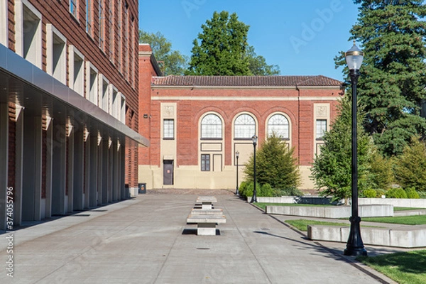 Obraz Publiczny kampus uniwersytecki w słoneczny dzień pokazujący nową i starą architekturę oraz otwarte przestrzenie bez obecnych studentów.