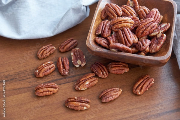 Fototapeta pecan nuts in wood bowl on old brown table, selective focus. top view. Healthy food and snack.