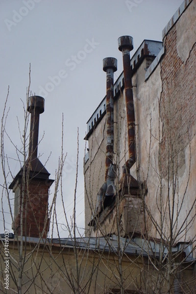 Obraz three rusty thin pipes on the roof against a gray overcast sky