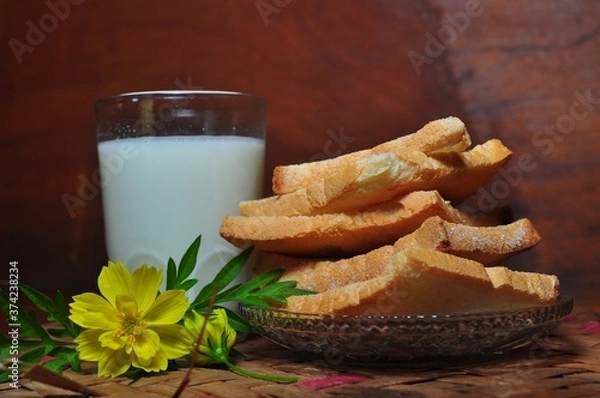 Fototapeta Dry rusk bread and a glass of milk isolated on wooden background. Healhty breakfast menu