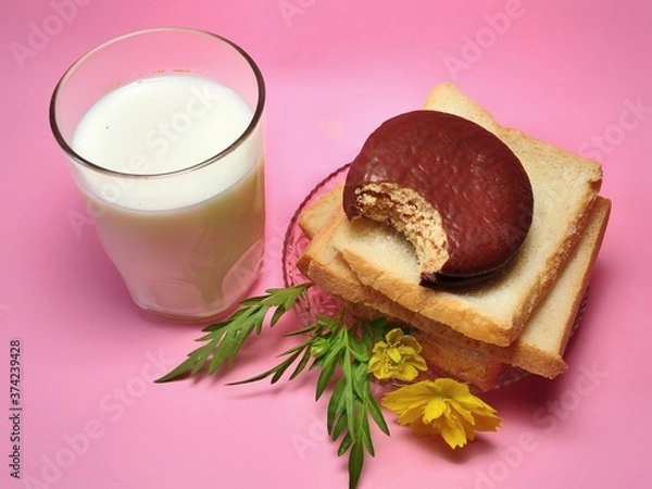 Fototapeta Dry rusk bread, choco pie chocolate and a glass of milk isolated on pink background. Healhty breakfast menu