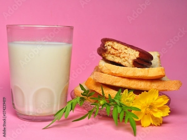 Fototapeta Dry rusk bread, choco pie chocolate and a glass of milk isolated on pink background. Healhty breakfast menu