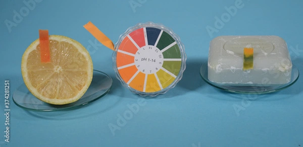Fototapeta Universal indicator paper for pH value is shown in use on a lemon with a pH value of approx. 2, and a piece of hand soap with a pH value of approx. 11