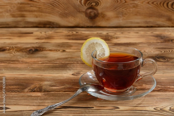 Obraz Glasses cup of tea with slices of lemon on a wooden table .
