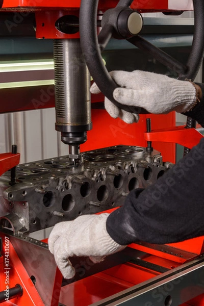 Obraz A craftsman sets up a machine for grinding car valves