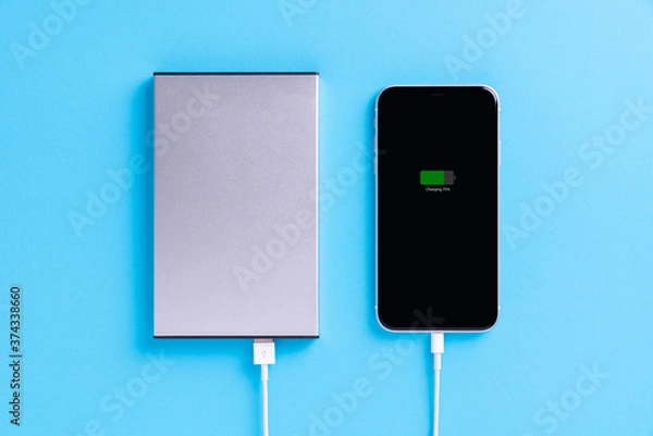 Fototapeta phone charging with external power supply on blue background