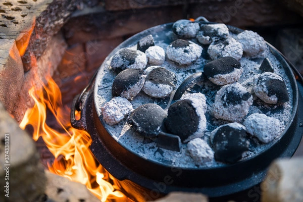 Fototapeta Dutch oven cooking in a campfire with glowing coal on the top