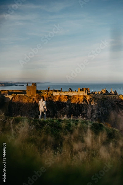 Fototapeta person in front of castle near the sea