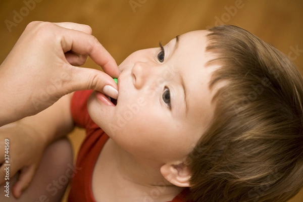 Fototapeta Mom feeding a sweet candy to her baby