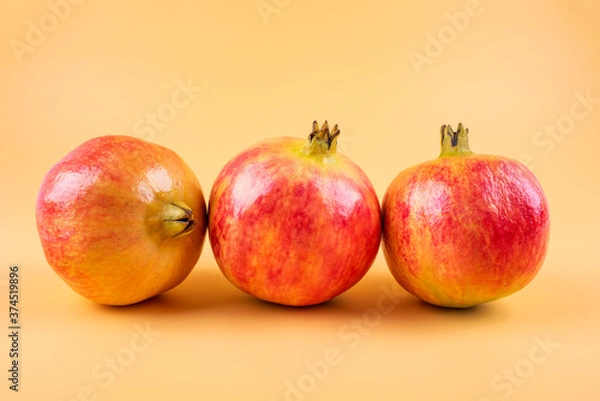 Fototapeta Three fresh pomegranate fruits on yellow background