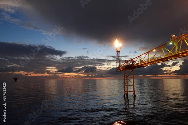 Fototapeta Fire on flare stack at oil and gas central processing platform while burning toxic and release over pressure from process