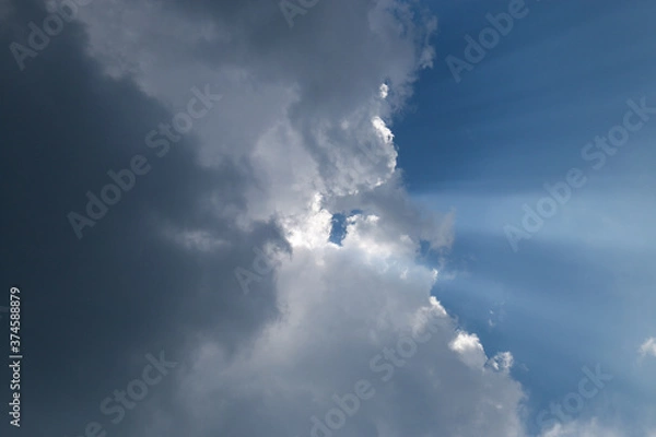 Fototapeta  heavenly light rays passing through clouds in blue sky