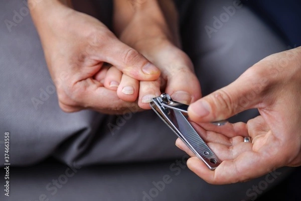 Obraz Man cuts his toenails with a Clipper
