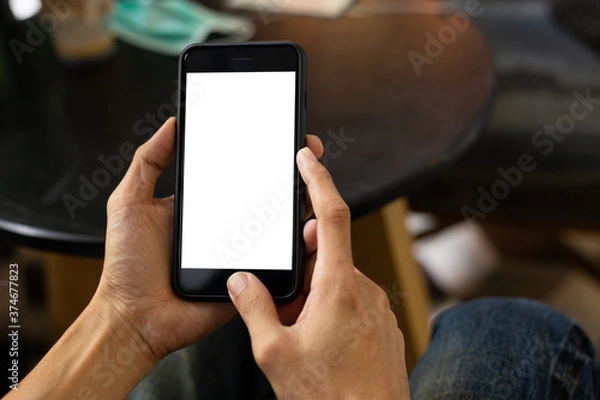 Fototapeta man hand using smartphone In the coffee shop,Screen blank with clipping path