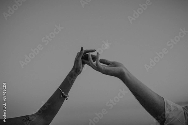 Fototapeta intertwined hands of a man and a woman on a gray background,