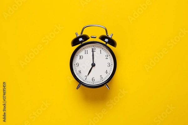 Fototapeta alarm clock shows 7 o'clock on a yellow background