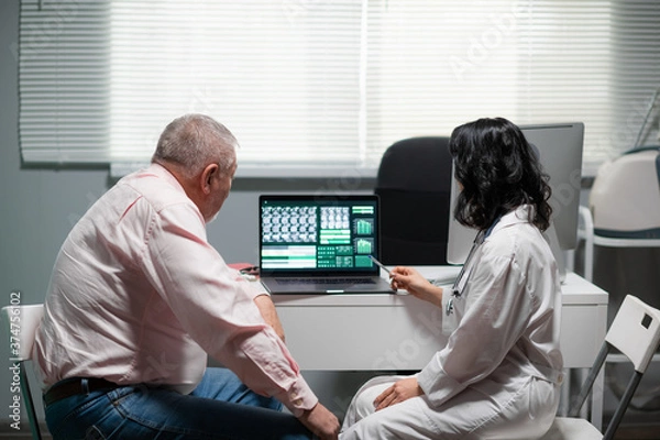 Fototapeta A man and a woman are looking at the x-ray on the monitor of the lap top.