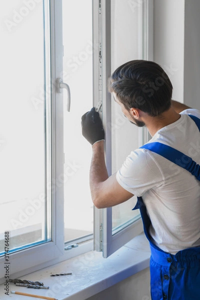 Fototapeta Worker in overalls preparing to install a window