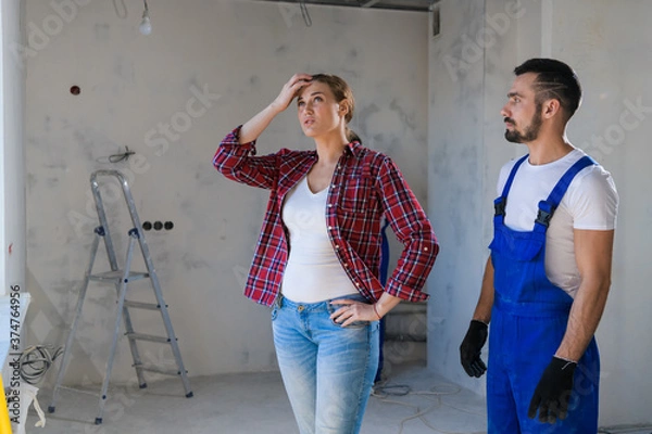 Fototapeta The foreman shows the client the renovation of the apartment. She is unhappy