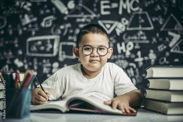 Fototapeta A boy with glasses man writing in the classroom