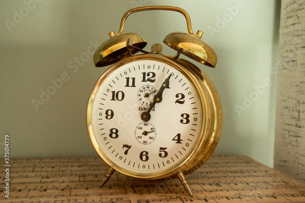 Fototapeta vintage alarm clock on music sheets by blue wall 