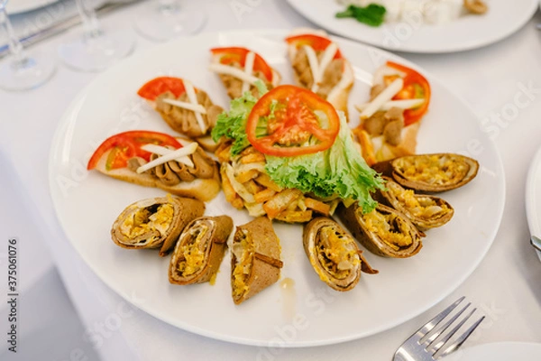 Fototapeta Pancakes with caviar in a white plate on the table. A delicious stylish dish. Serves dinner on a festive table. Food on festive table at wedding banquet.
