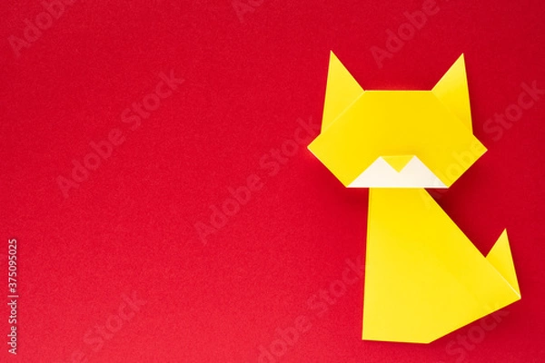 Obraz yellow origami cat on red background
