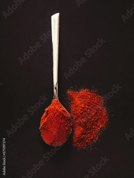 Obraz Silver teaspoon with hot red chilli pepper on a black background.