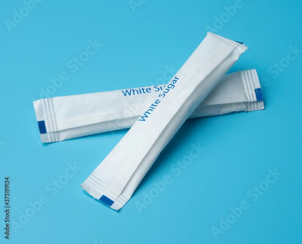 Obraz White sugar packets on a blue background.