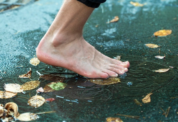 Fototapeta teen walks through puddles after summer rain