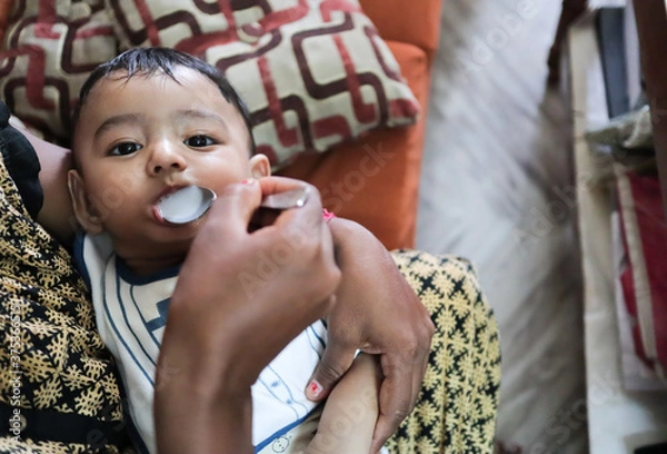 Obraz an infant toddler baby boy after weaning eating solid food with spoon
