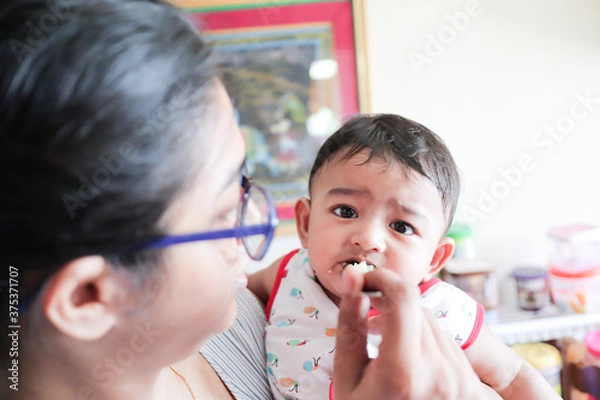 Obraz an infant toddler baby boy not enjoying while feeding solid food. irritated expression