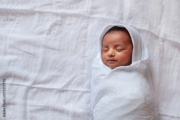 Obraz a one month old baby sleeping and swaddled in white cloth lying in white cloth background