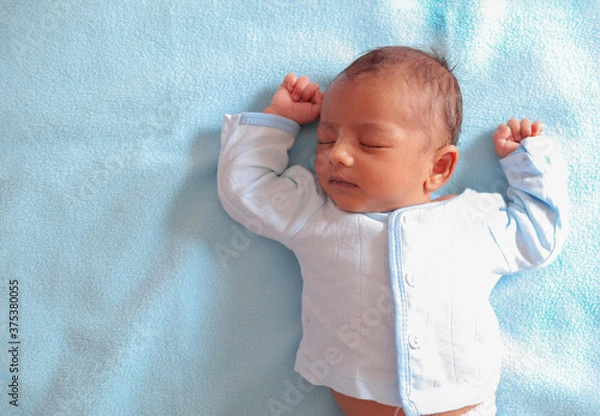 Obraz a neonatal infant baby sleeping in peace on a sky colored towel with copy space for text