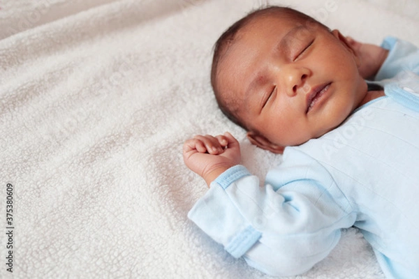 Obraz a one month old baby sleeping and swaddled in white cloth lying in white cloth background