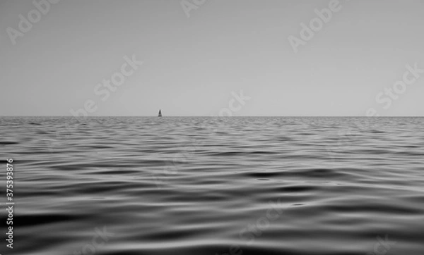 Fototapeta black and white seascape of calm sea with sails boat in the background - peace and relax concept.