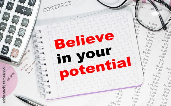 Obraz Business concept. Notebook with text Believe in your potential heet of white paper for notes, calculator, glasses, pencil, pen, in the white background
