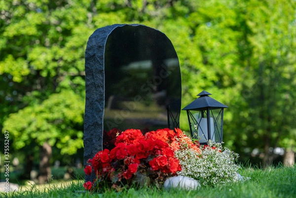 Fototapeta Black gravestone with red and white flowers and without name inscription, on a well cared cemetery in Sweden