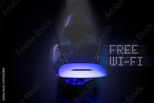 Fototapeta A hacker is holding a Wi-Fi router on a black background.