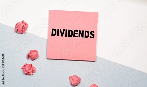 Obraz DIVIDENDS the inscription on the pink sticker, next to scattered crumpled papers. white-and-blue background. Business concept
