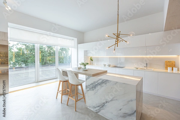 Obraz luxury interior design of modern trendy snow white kitchen in minimalistic style with island and two bar stools. huge windows to the floor and a glass rack for dishes