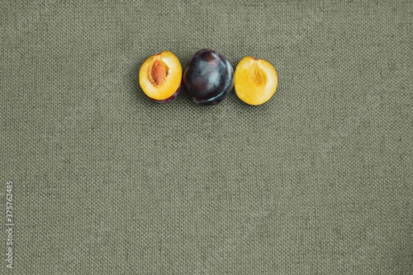 Fototapeta Whole plum and sliced plum on a table cloth; Fresh plums prepared to eat