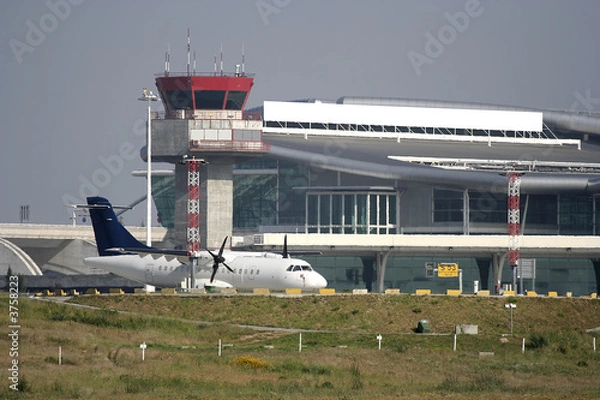 Obraz airplane parked at the airport near the tower
